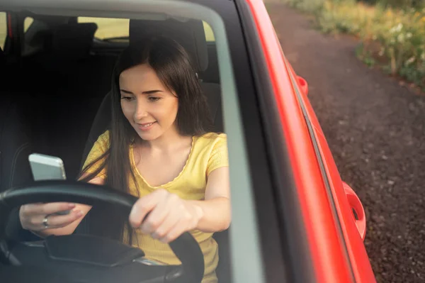 Young Woman Using Smartphone While Driving Car — Stockfoto