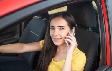 Genç bayan araba kullanırken akıllı telefon kullanıyor..