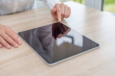 Digital tablet computer with a blank screen in the hands on wooden table
