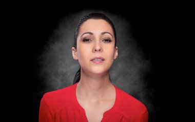 Portrait of a young beautiful brunette woman in red clothes on a dark background.