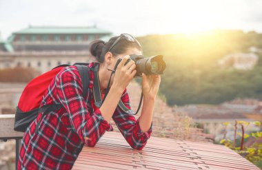 A woman photographer with a backpack makes a photo while traveling.