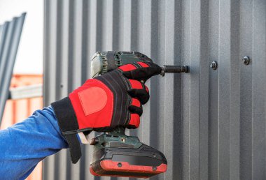 The master works as a wrench with a profiled sheet. The specialist fastens the corrugated board.