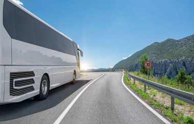 Beyaz bir turist otobüsü otoban boyunca güzel bir manzaranın arka planına doğru ilerliyor..