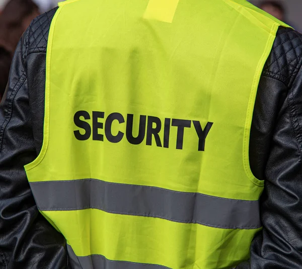 Security. Close-up of a yellow guards vest.