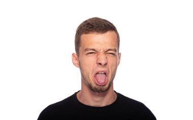 Genç bir adam ve beyaz bir arka planda suratını buruşturuyor..