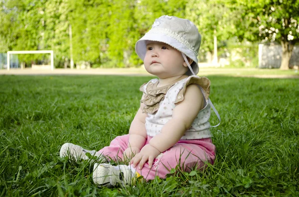 Yeşil çimenlerin üzerinde oturan küçük bebek — Stok fotoğraf