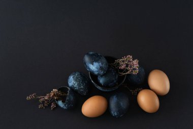 Siyah arka planda dokuz Paskalya yumurtası ve kurutulmuş çiçek kompozisyonu.