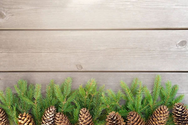 Noel ağacı ahşap arka planda eski gri panolar ve altında koniler olan köknar dalları, boş alanlı eko tarzı noel afişi