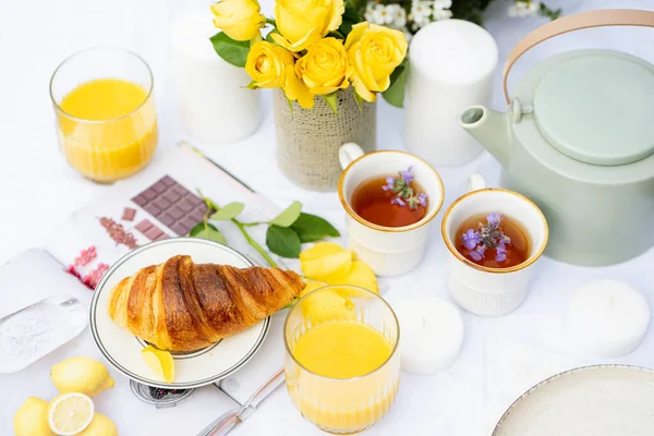 Croissant Orange Juice Herbal Tea Two Cups Teapot Table White — Zdjęcie stockowe