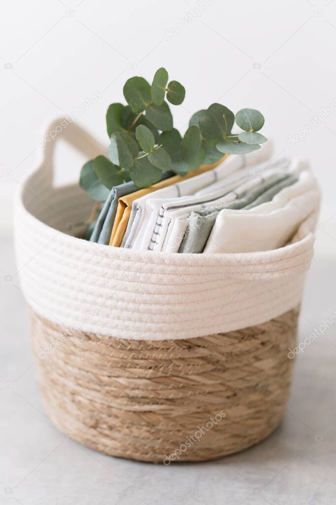 wicker basket with textile of pastel colors and eucalyptus in white room