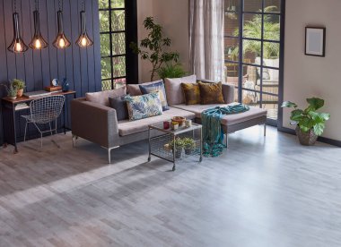 Bahçe manzarasının önündeki modern gri kanepe ve ahşap arka plan duvarı, bitki ve orta masa vazosu, ev tasarımı..