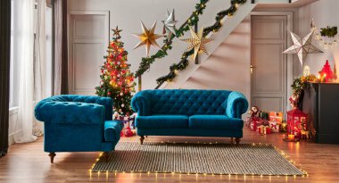 Çam ağacı hediye kutusu ve şöminesi olan modern kanepe Noel konsepti dekoratif lamba, merdiven ve kapı arka planı, gri duvar, hasır halı tasarımı.