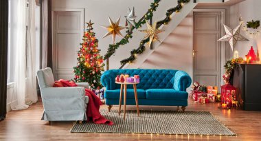 Çam ağacı hediye kutusu ve şöminesi olan modern kanepe Noel konsepti dekoratif lamba, merdiven ve kapı arka planı, gri duvar, hasır halı tasarımı.