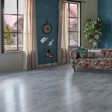 Mavi duvar kağıdı odasındaki çiçek desenli kanepe, yeşil bitki vazosu, saat ve perde, parke zemin modern oda..