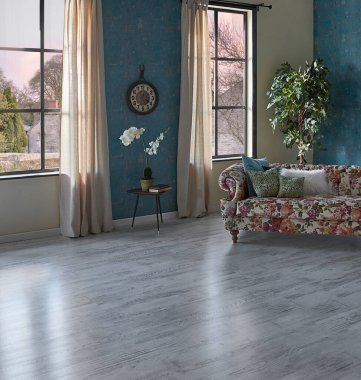 Mavi duvar kağıdı odasındaki çiçek desenli kanepe, yeşil bitki vazosu, saat ve perde, parke zemin modern oda..