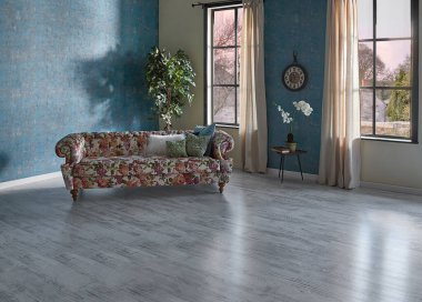 Mavi duvar kağıdı odasındaki çiçek desenli kanepe, yeşil bitki vazosu, saat ve perde, parke zemin modern oda..