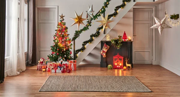 Modern sofa Christmas New Year concept with pine tree gift box and fireplace, decorative led lamp, stairs and door background, grey wall, wicker carpet design.