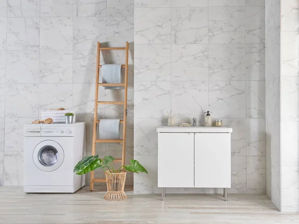Modern bath room with washing machine and cabinet sink style, mirror on the wall, wooden stairs towel decor, dirty clothes in the basket.