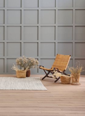 Vase of cotton flower and wicker chair decoration in front of the modern grey wall, carpet style.