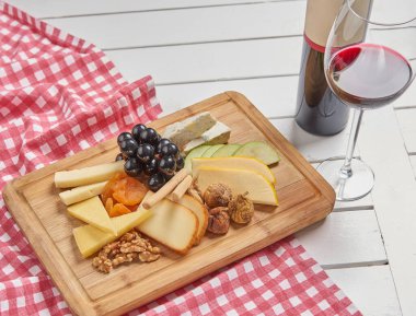 Cheese on the wooden cutting board presentation menu with wine.