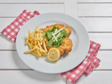 Schnitzel on the place with fried potato in the plate and sauce background.