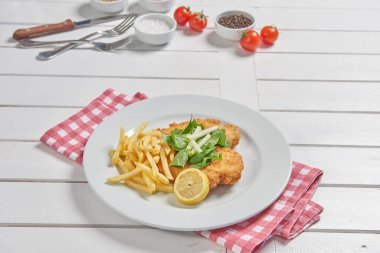 Schnitzel on the place with fried potato in the plate and sauce background.
