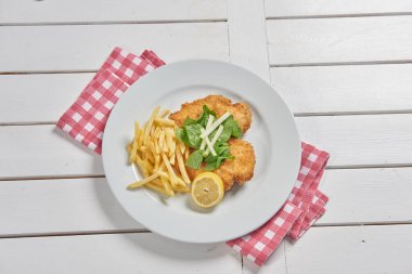 Schnitzel on the place with fried potato in the plate and sauce background.