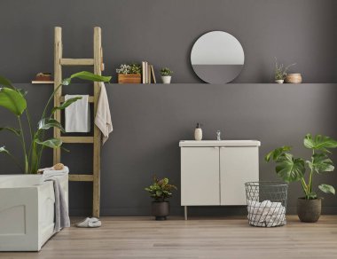 Modern banyo odası dolabı, lavabo, ayna ve küvet tarzı gri duvar fonu, vazo, bitki, çamaşır, havlu ve ahşap merdiven süslemeleri..