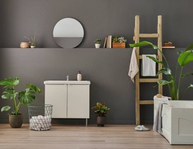 Modern banyo odası dolabı, lavabo, ayna ve küvet tarzı gri duvar fonu, vazo, bitki, çamaşır, havlu ve ahşap merdiven süslemeleri..