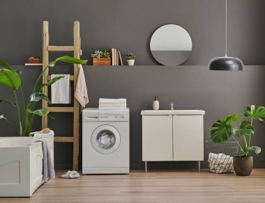 Modern banyo odası dolabı, lavabo, ayna ve küvet tarzı gri duvar fonu, vazo, bitki, çamaşır, havlu ve ahşap merdiven süslemeleri..