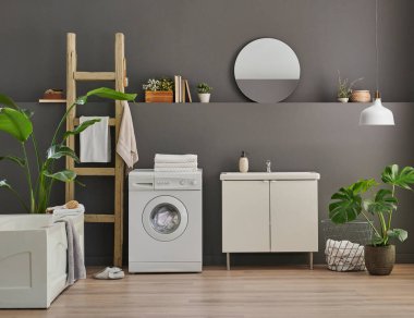 Modern banyo odası dolabı, lavabo, ayna ve küvet tarzı gri duvar fonu, vazo, bitki, çamaşır, havlu ve ahşap merdiven süslemeleri..