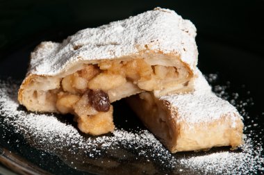 siyah bir zemin üzerine pudra şekeri ile kaplı lezzetli elma strudel.