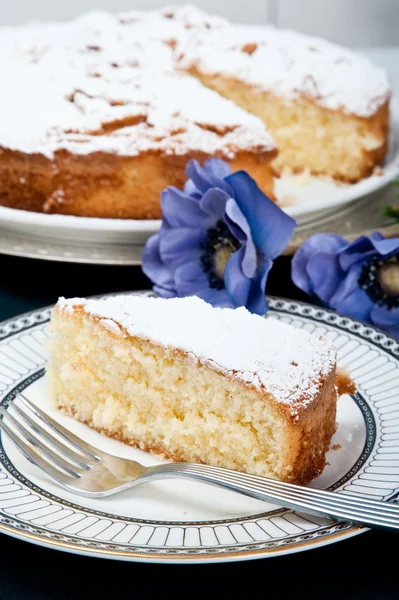 En tallrik med en bit av en äppelkaka med den stora kakan på bakgrunden. blommor som färskhet kakan. — Stockfoto