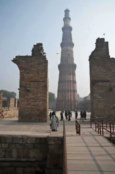 The Qutab Minar In New Delhi, Índia. As pessoas estão visitando as ruínas e caminhando na frente do famoso Qutab Minar . — Fotografia de Stock