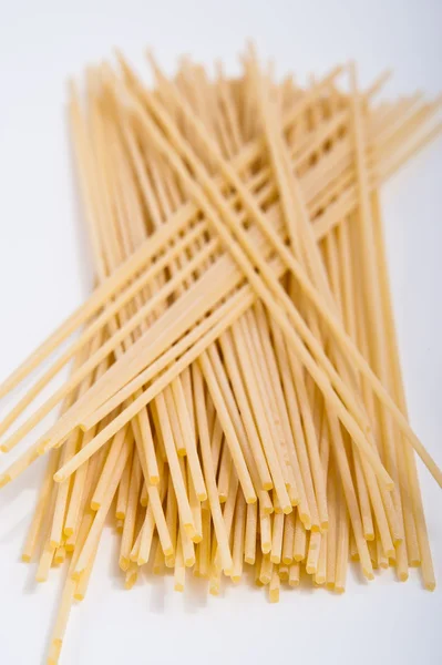 Bando de espaguete no fundo branco pronto para ser cozido em uma receita italiana — Fotografia de Stock