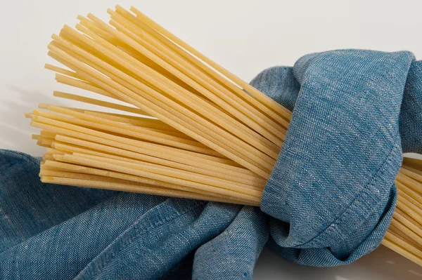 Bando de espaguete em um blu guardanapos leves prontos para cozinhar uma receita italiana . — Fotografia de Stock
