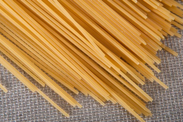 Bando de espaguete em uma toalha de mesa bege pronta para ser cozida em uma receita italiana — Fotografia de Stock
