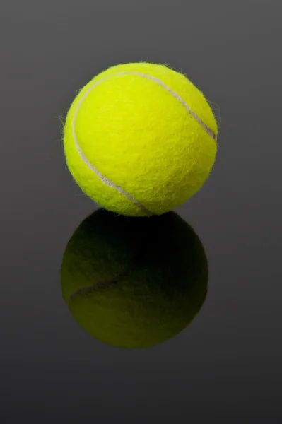 Bola de tênis amarelo no fundo preto com sombra — Fotografia de Stock