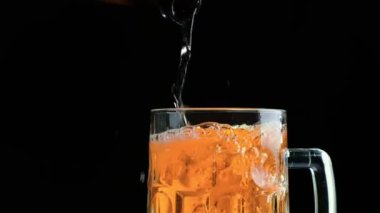 Su damlalarıyla dolu bir bardakta soğuk bira. Şişeden bira dökülüyor.. 