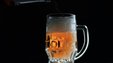 Su damlalarıyla dolu bir bardakta soğuk bira. Şişeden bira dökülüyor.. 