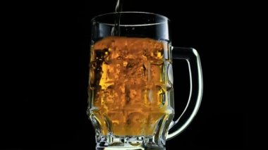 Su damlalarıyla dolu bir bardakta soğuk bira. Şişeden bira dökülüyor.. 