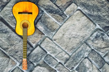 Gri tuğla kaldırımda akustik sarı gitar
