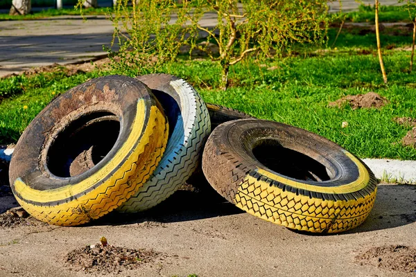 Três velhos pneus pintados num relvado verde — Fotografia de Stock