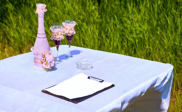 婚礼香槟酒瓶和户外餐桌上的酒杯 — 图库照片