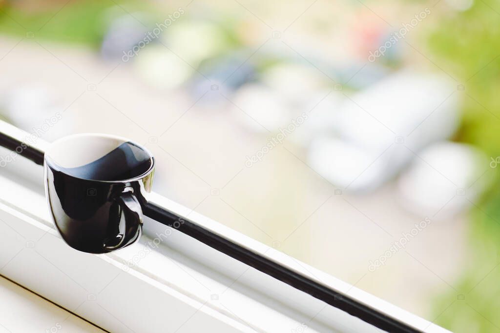 Black cup for coffee or tea on a white windowsill