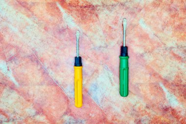 Yeşil ve turuncu tornavidalar kahverengi mermer kiremitler üzerinde