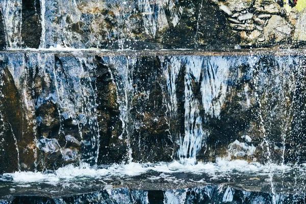 L'eau pure bleue minérale coule sur les pierres de montagne — Photo