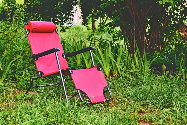 Sedia chaise lounge rossa sul prato verde estivo — Foto Stock