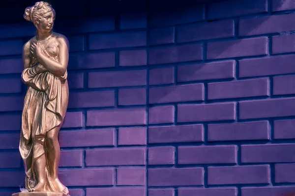 Goldene Bronzestatue einer antiken Frau und Backsteinhintergrund für Text — Stockfoto