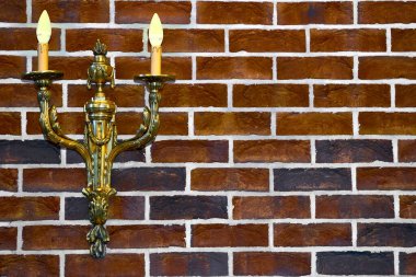 Kırmızı tuğla duvarda çift altın şamdan lambası